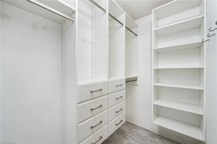 Primary bedroom walk in closet with custom built closet organizer
