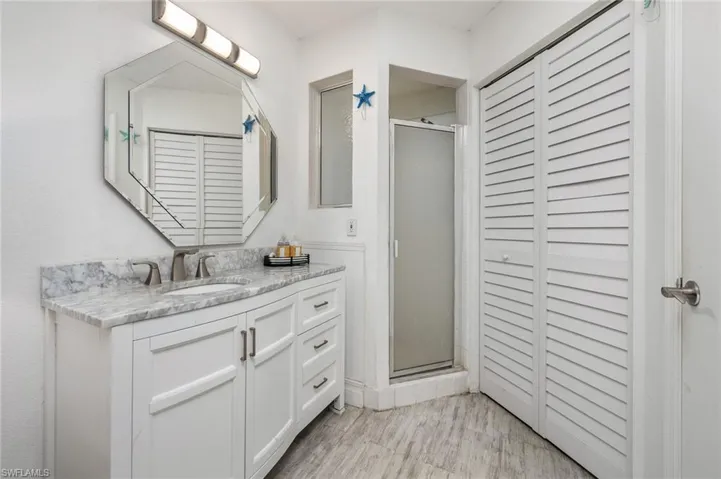Primary bathroom featuring a closet, vanity, and a shower stall