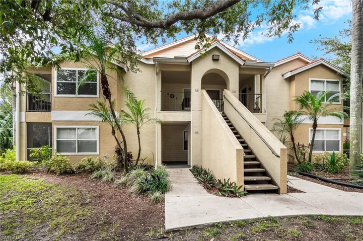 View of front of building featuring stairway, stucco siding, and a balcony.  This unit is on the first floor.
