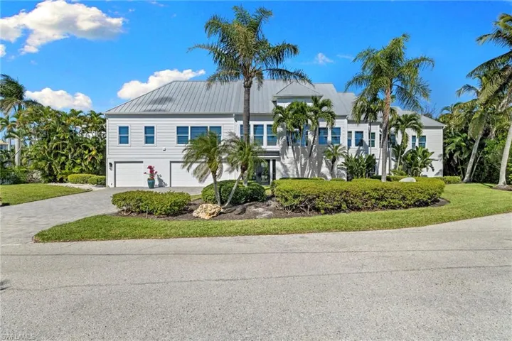 Coastal inspired home featuring decorative driveway, a garage, a metal roof, and a front lawn