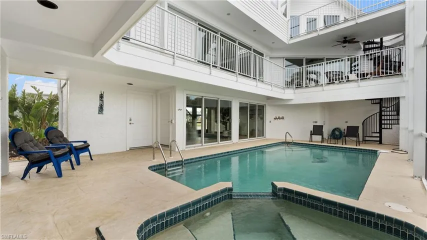 View of swimming pool featuring a patio area, a pool with connected hot tub, a balcony, stairway, and a ceiling fan