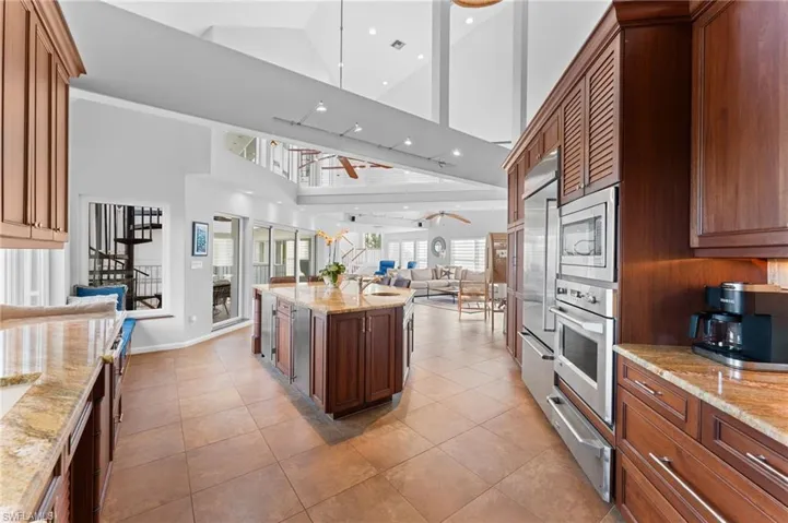 Kitchen with light stone countertops, a warming drawer, open floor plan, high vaulted ceiling, and built in appliances