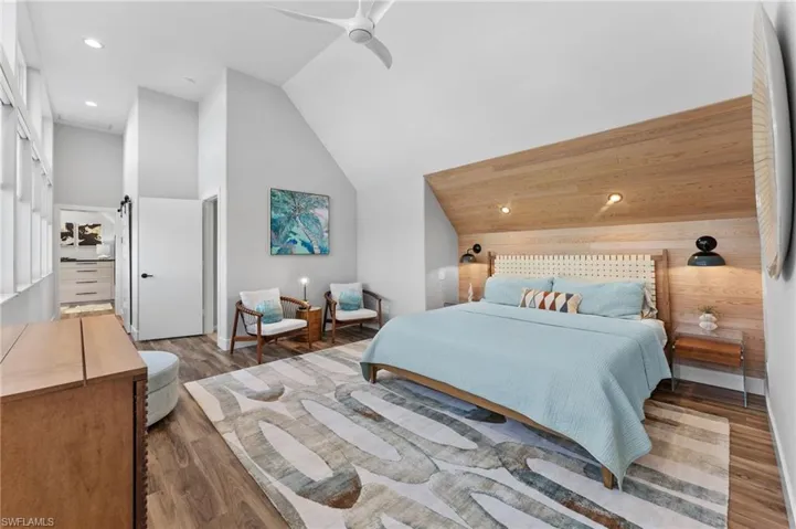 Bedroom featuring recessed lighting, high vaulted ceiling, a ceiling fan, wood finished floors, and wood walls