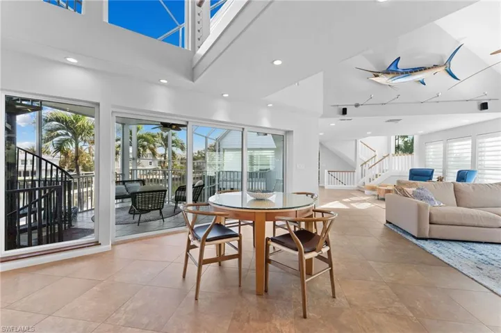 Dining space with high vaulted ceiling, stairs, recessed lighting, a ceiling fan, and light tile patterned flooring