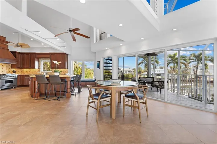 Dining area with a high ceiling, a ceiling fan, recessed lighting, and light tile patterned floors