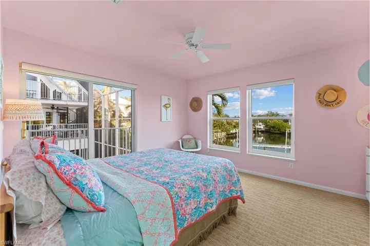 Carpeted bedroom featuring a water view, ceiling fan, and access to exterior
