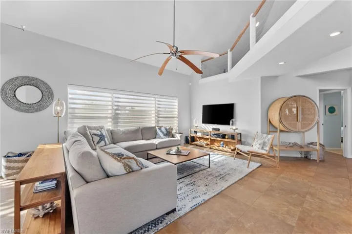 Living area with a ceiling fan, recessed lighting, and high vaulted ceiling