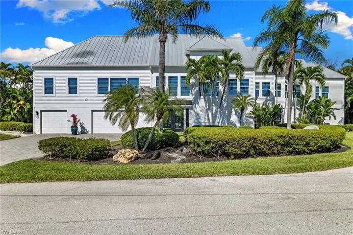 Beach home with a metal roof, driveway, an attached garage, and a standing seam roof