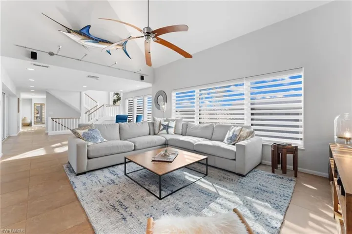 Living room with a ceiling fan, stairway, a high ceiling, and plenty of natural light