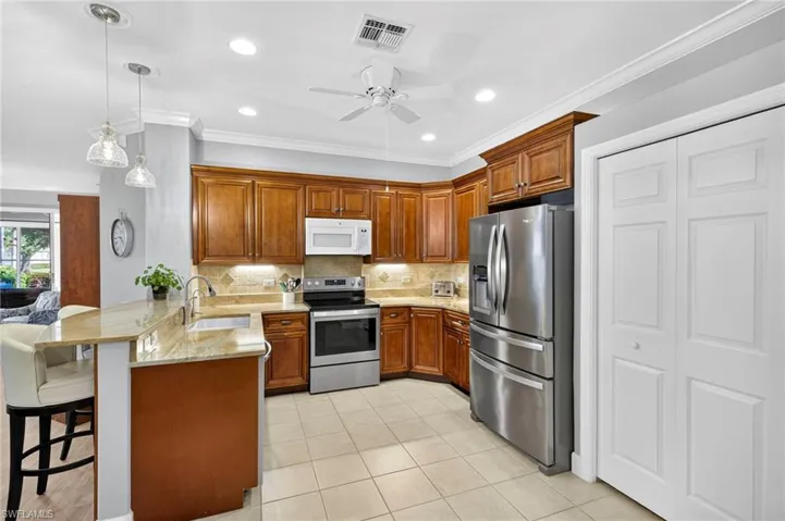 Kitchen featuring a peninsula, a kitchen breakfast bar, brown cabinets, recessed lighting, and ornamental molding