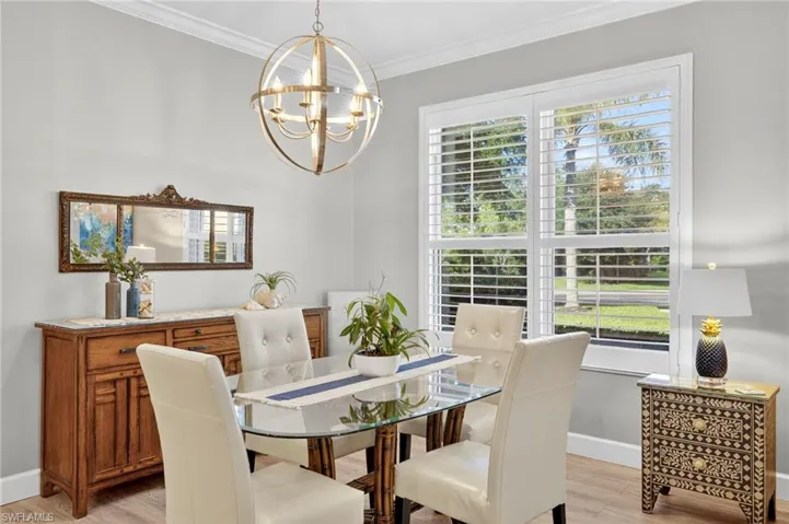 Dining room with crown molding, light wood-type flooring, and a chandelier