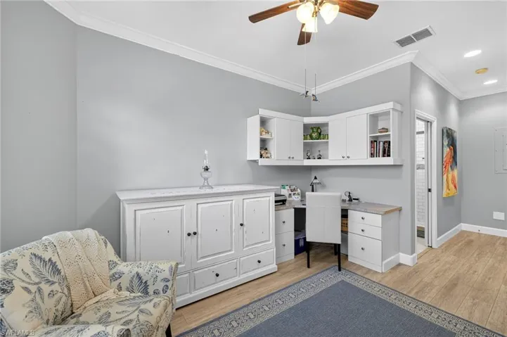 Guest Bedroom/Office space featuring crown molding, light wood-type flooring, built in desk, and a ceiling fan