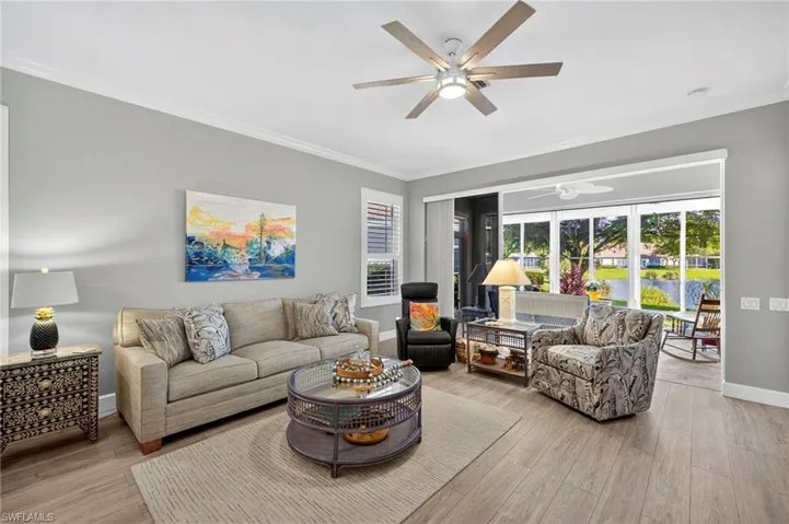 Living room featuring crown molding, a water view, light wood-style floors, and a ceiling fan