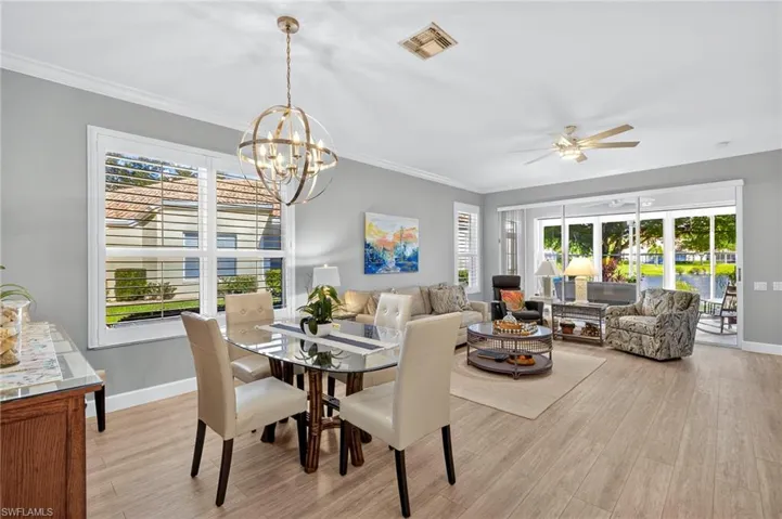 Dining room featuring crown molding, light wood-style floors, ceiling fan, and a chandelier