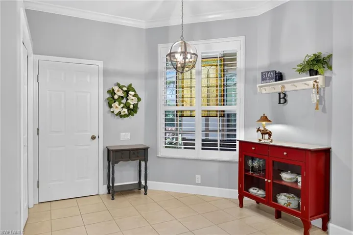 Foyer entrance with light tile patterned floors, a chandelier, and ornamental molding