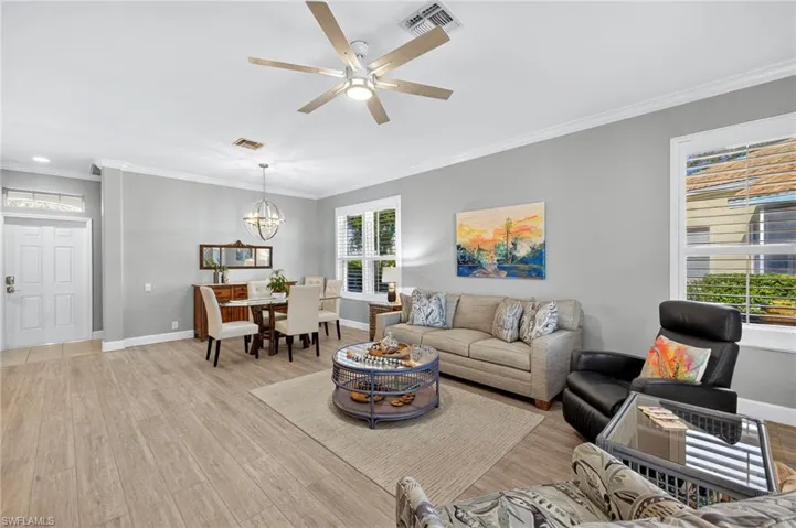 Living area with ornamental molding, light wood finished floors, a chandelier, and a ceiling fan