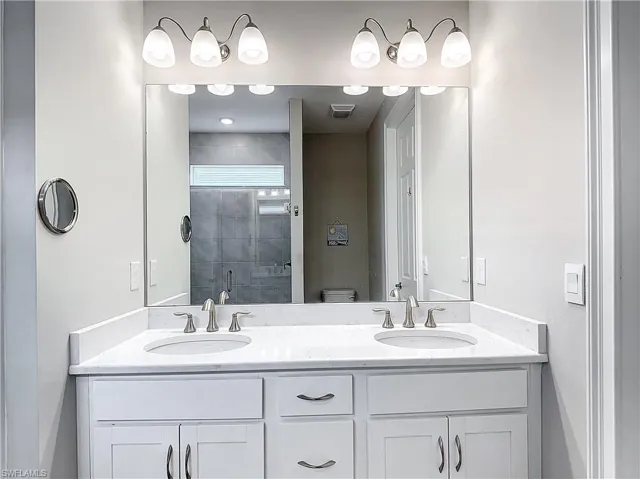 Full bathroom featuring a stall shower, double vanity, and toilet