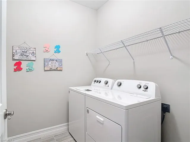 Laundry room with washer and clothes dryer and baseboards