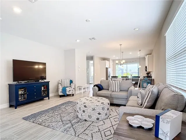Living room featuring a chandelier, baseboards, light wood finished floors, and recessed lighting