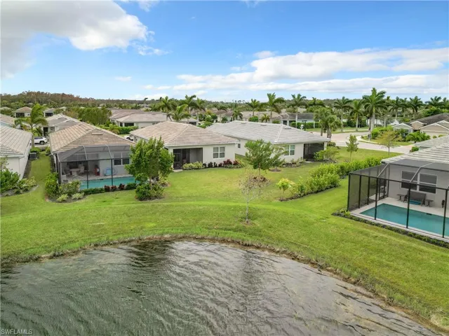 Aerial perspective of suburban area featuring a pool and a large body of water