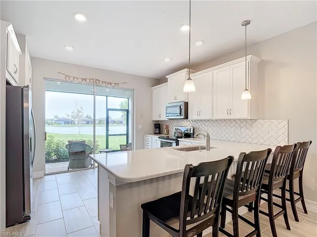 Kitchen featuring appliances with stainless steel finishes, a sink, tasteful backsplash, a peninsula, and light countertops