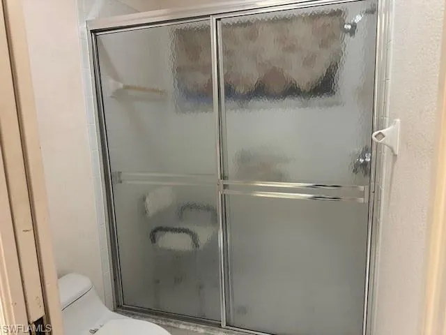 Full bathroom featuring an enclosed shower and a textured wall