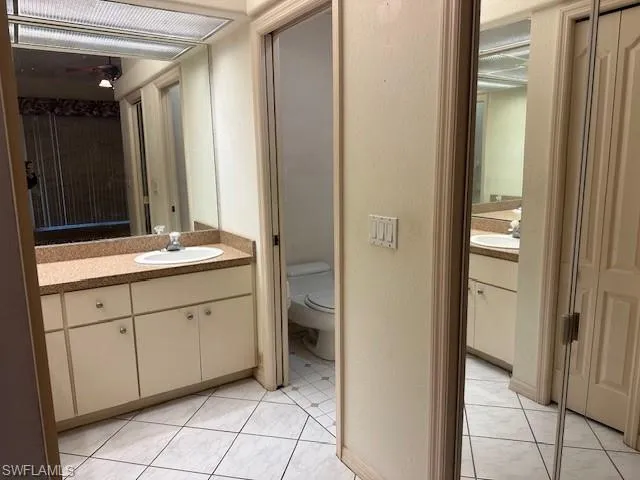 Full bathroom featuring vanity, a textured wall, and light tile patterned flooring