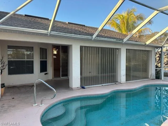 Outdoor pool with a patio area and glass enclosure