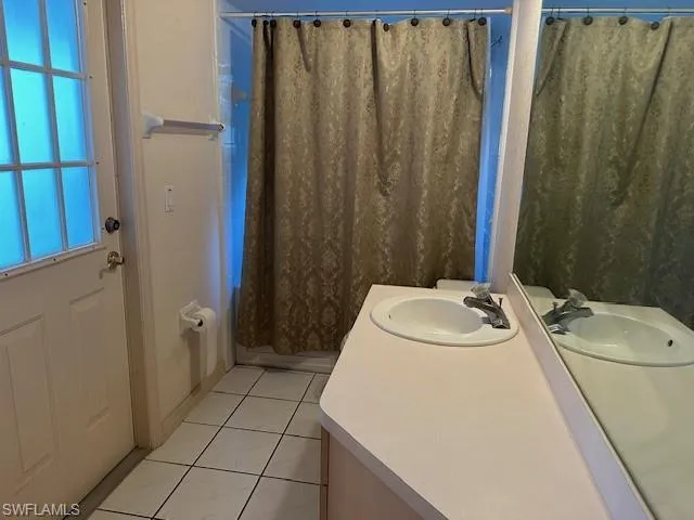 Full bath with vanity, a shower with curtain, and light tile patterned floors
