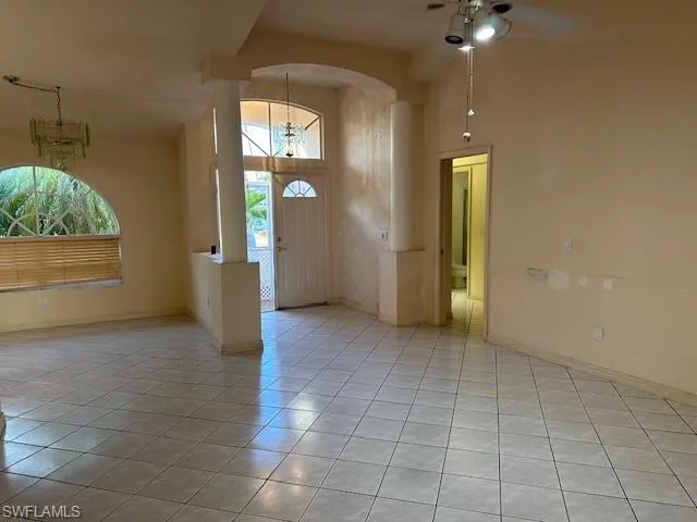 Foyer entrance featuring a high ceiling, ceiling fan, hanging lights, light tile patterned flooring, and arched walkways