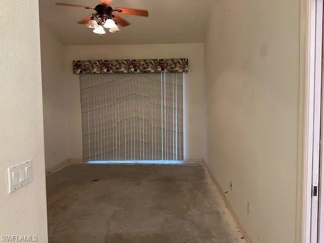 Empty room featuring ceiling fan, a textured wall, and unfinished concrete flooring