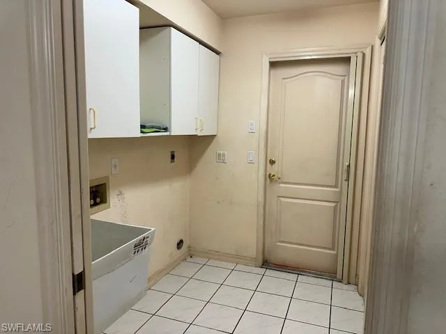 Laundry area with washer hookup, cabinet space, hookup for an electric dryer, and light tile patterned floors
