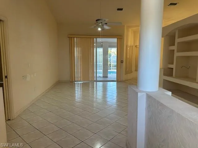 Spare room featuring built in features, ceiling fan, and light tile patterned flooring