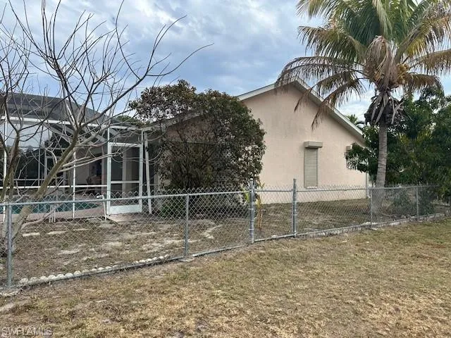 View of side of home featuring stucco siding and a gate
