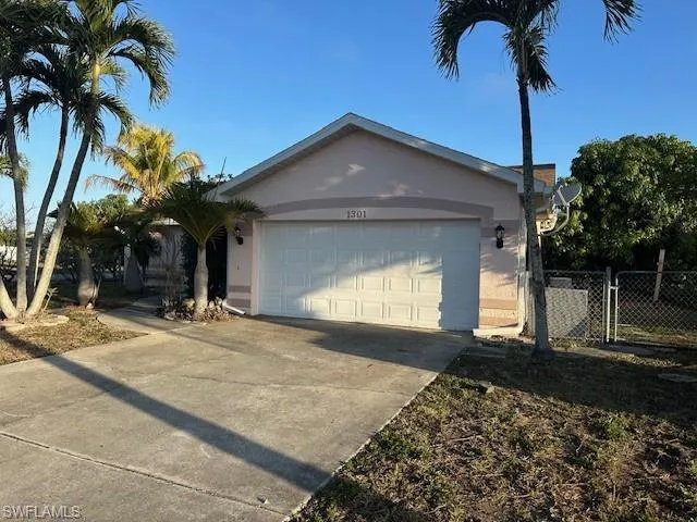 Ranch-style home featuring driveway, stucco siding, a gate, and an attached garage