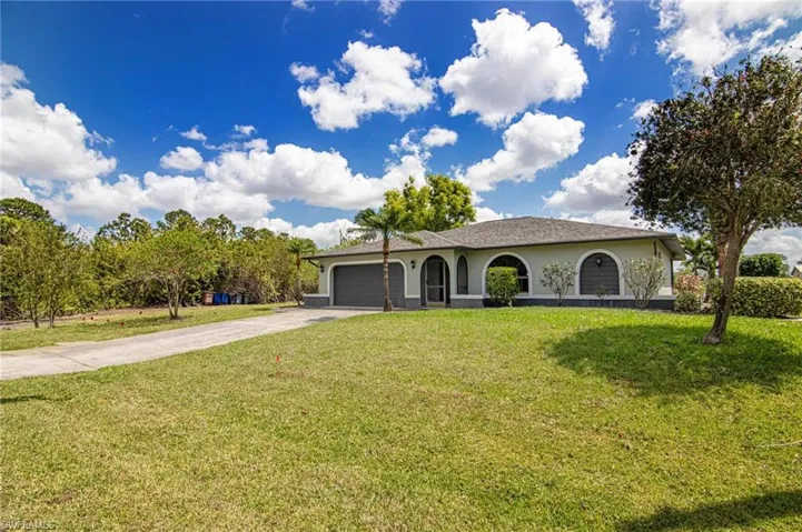 View of front of home with a garage, driveway, stucco siding, and a front lawn