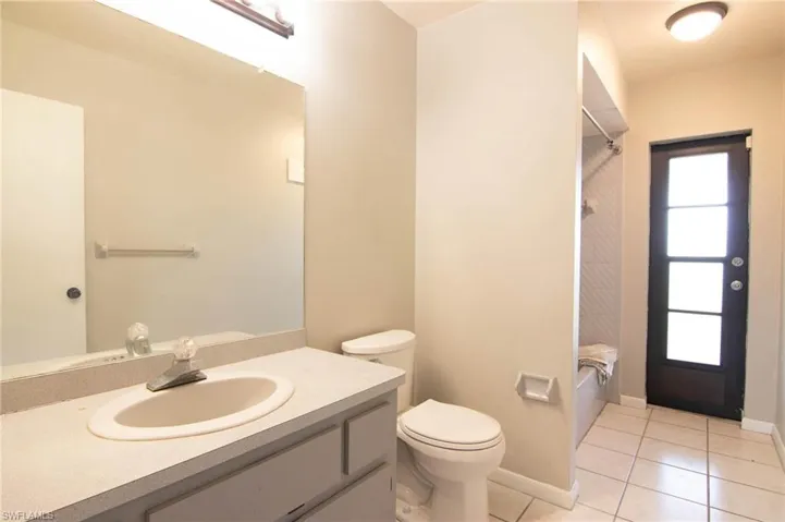 Bathroom with vanity, toilet, washtub / shower combination, tile patterned floors, and baseboards