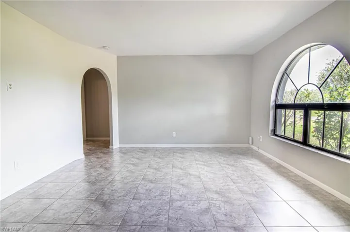 Empty room featuring arched walkways and baseboards
