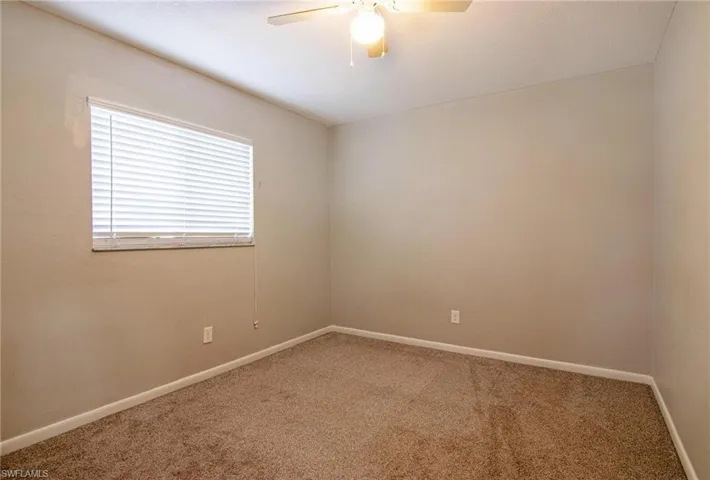 Carpeted empty room with baseboards and a ceiling fan