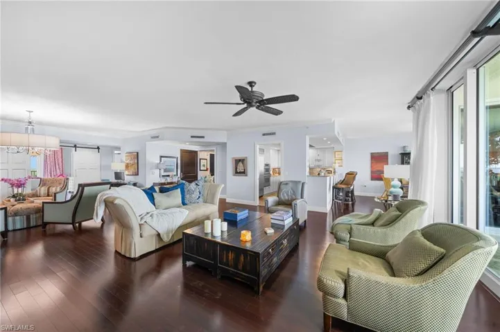 Living room with ornamental molding, dark hardwood / wood-style flooring, ceiling fan, and a barn door