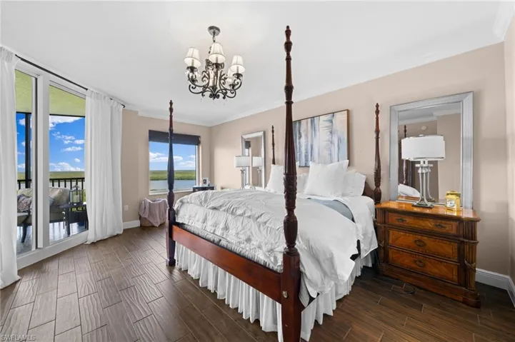 Bedroom with crown molding, dark hardwood / wood-style flooring, access to outside, and a notable chandelier