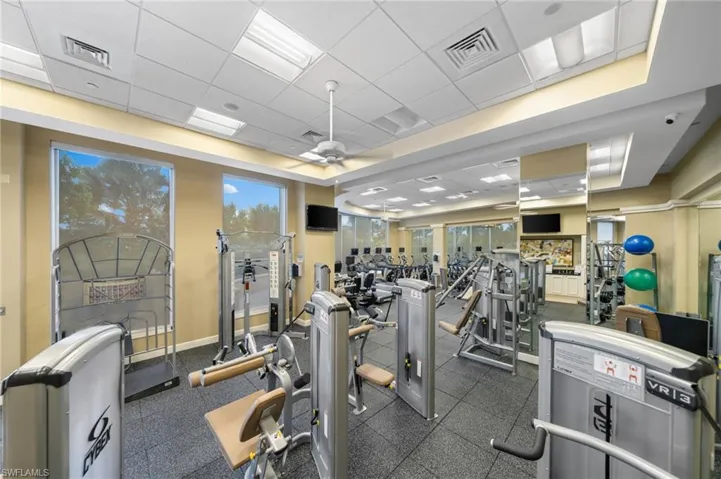 Exercise room with ceiling fan and a drop ceiling