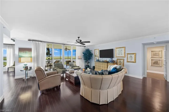 Living room with ceiling fan, dark hardwood / wood-style flooring, and crown molding