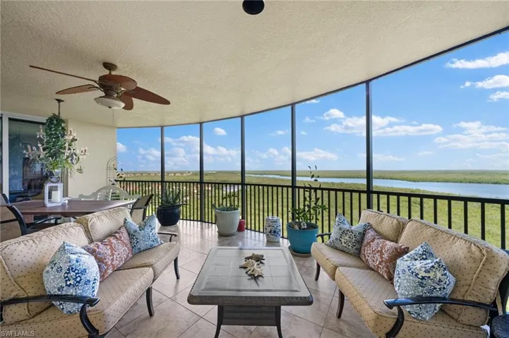 Sunroom / solarium with ceiling fan and a water view