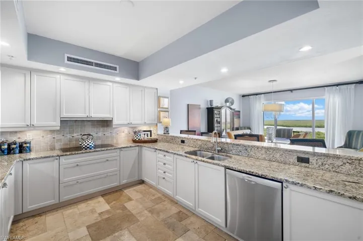 Kitchen with black electric stovetop, dishwasher, white cabinetry, and sink