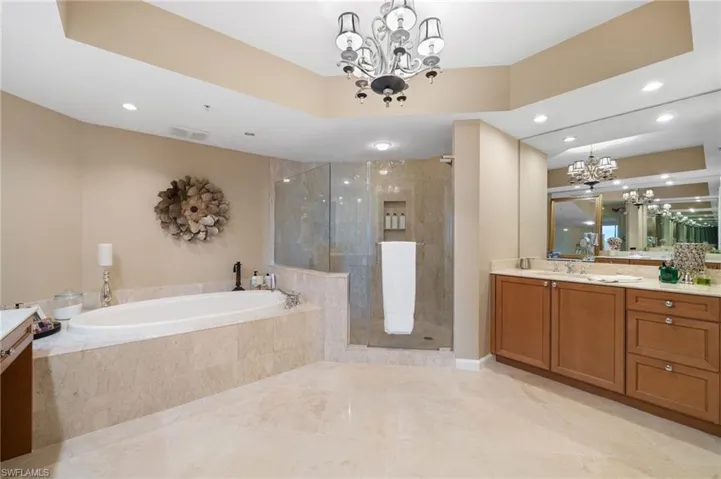 Bathroom featuring vanity, an inviting chandelier, and shower with separate bathtub