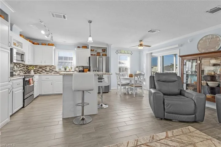 Kitchen with white cabinetry, appliances with stainless steel finishes, ceiling fan, a center island, and pendant lighting