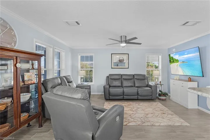Living room featuring ornamental molding, light hardwood / wood-style floors, a textured ceiling, and a healthy amount of sunlight