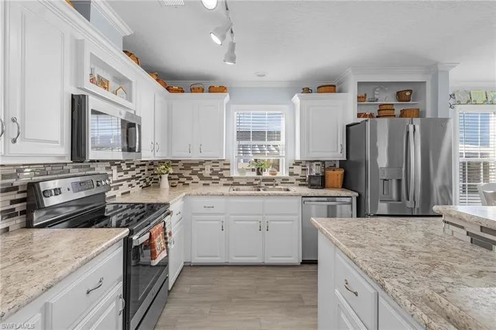 Kitchen featuring white cabinetry, appliances with stainless steel finishes, sink, and a healthy amount of sunlight