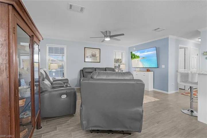 Living room with light hardwood / wood-style floors, ceiling fan, a healthy amount of sunlight, and a textured ceiling